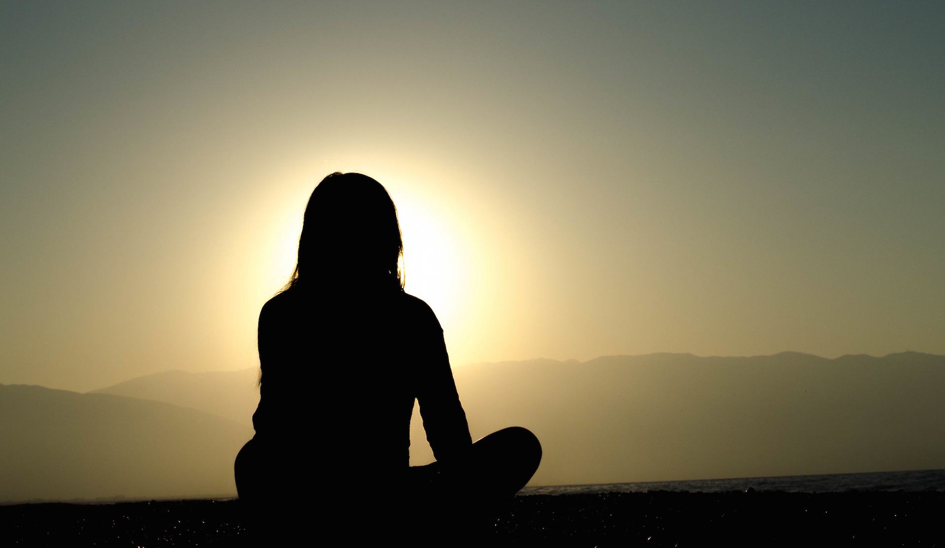 silhouette of woman facing sunset