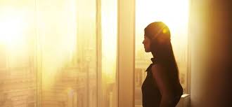 silhouette woman looking out golden city window